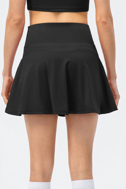 The back view of a model wearing a high-waist active skirt in black, showcasing the wide waistband and flared silhouette.