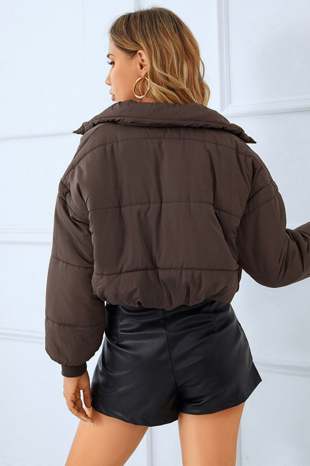  Woman in a brown puffer jacket and black leather shorts, 