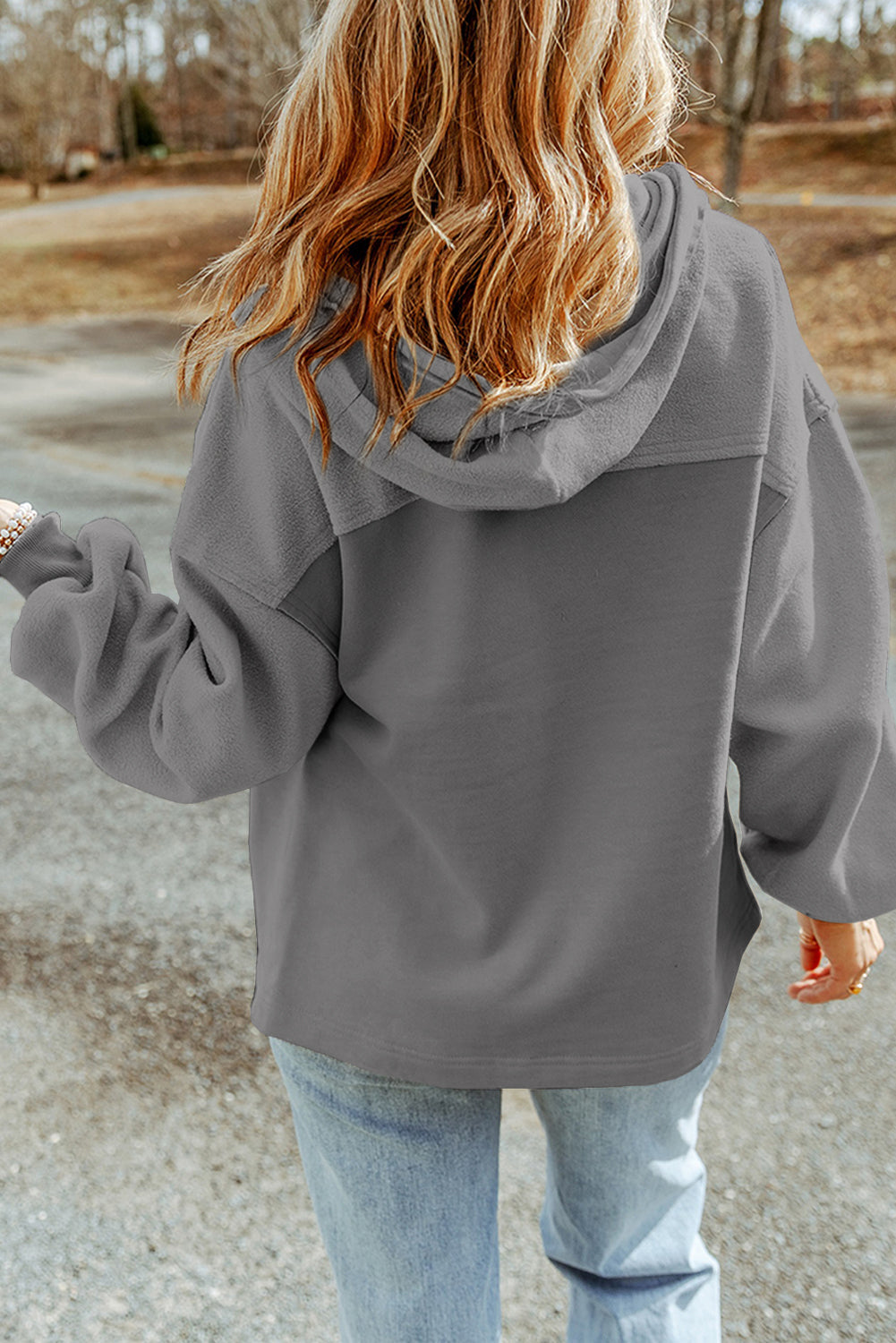 Woman wearing a gray jacket and light blue jeans set against an outdoor backdrop.