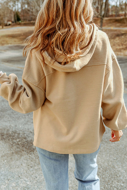 Woman wearing a tan jacket and light blue jeans set against an outdoor backdrop.