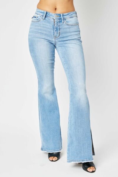 Light-wash flared jeans paired with black open-toe heels, shown on a person against a plain background.