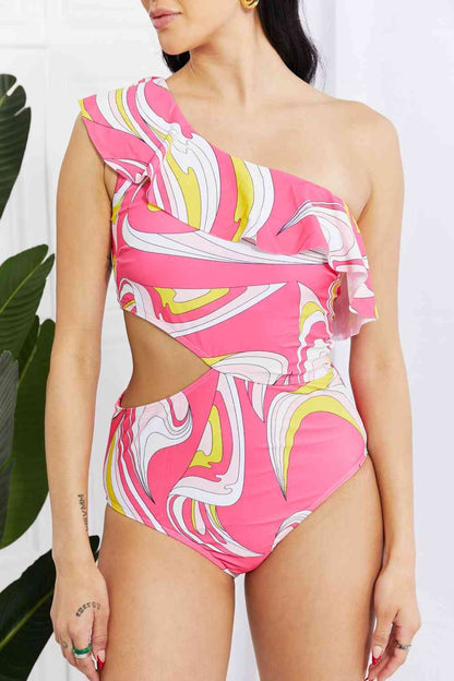 Close-up of pink asymmetric cutout swimsuit with ruffle trim and vibrant swirl pattern, highlighting the one-shoulder design and detailed print.